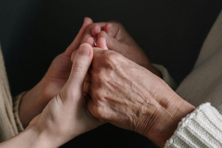Young persons hand holding elderly persons hands