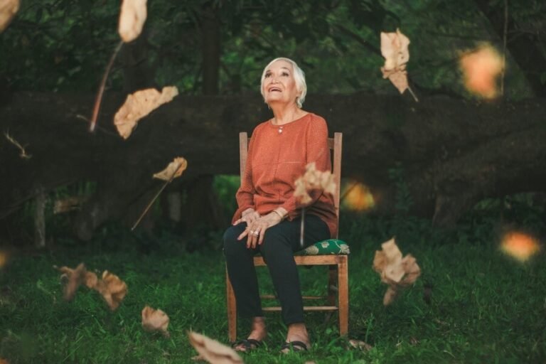 Alzheimer's elderly lady enjoying watching leaves falling from the trees