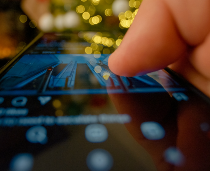 A close up of a someone clicking in a mobile phone with xmas lights in the background