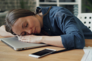 Woman at desk sleeping next to laptop