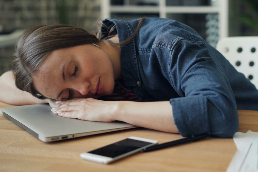 Woman at desk sleeping next to laptop
