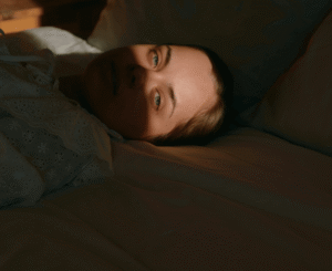 Girl in bed awake with light shining directly into her eyes