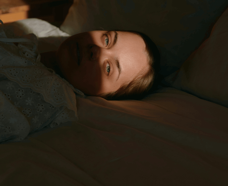Girl in bed awake with light shining directly into her eyes